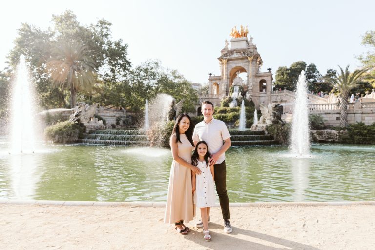 A family wearing soft pastel colors posing for a photo in front of a fountain at Ciutadella Park
