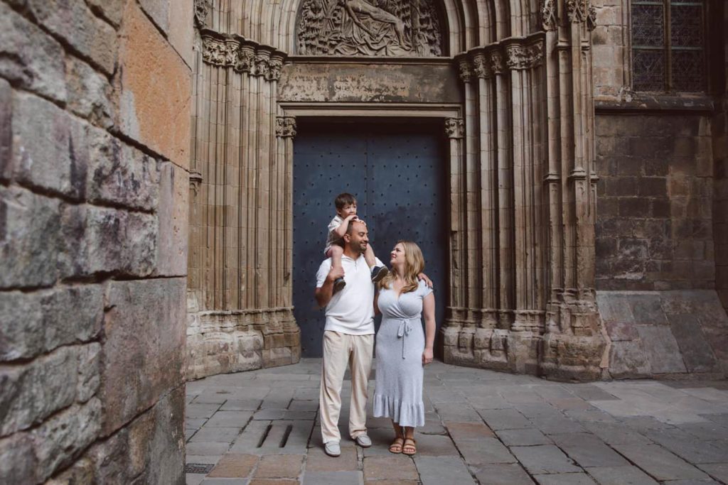 Family in soft neutral outfits during a photo session at the Gothic Quarter in Barcelona.